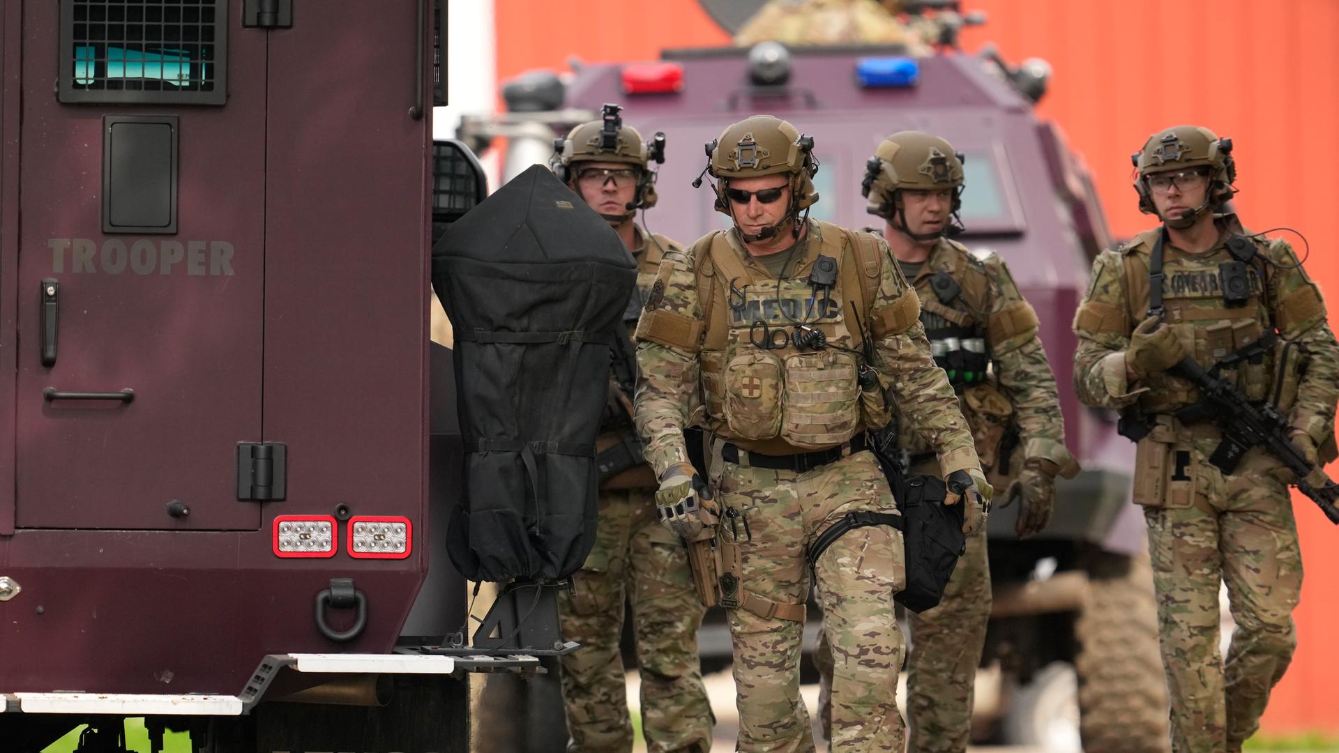 Mehrere Soldaten stehen neben einem Fahrzeug während der Suche nach dem Attentäter, der eine Politikerin der Demokraten und ihren Mann erschoss.