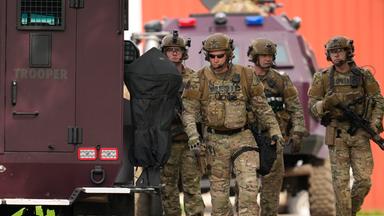 Mehrere Soldaten stehen neben einem Fahrzeug während der Suche nach dem Attentäter, der eine Politikerin der Demokraten und ihren Mann erschoss.