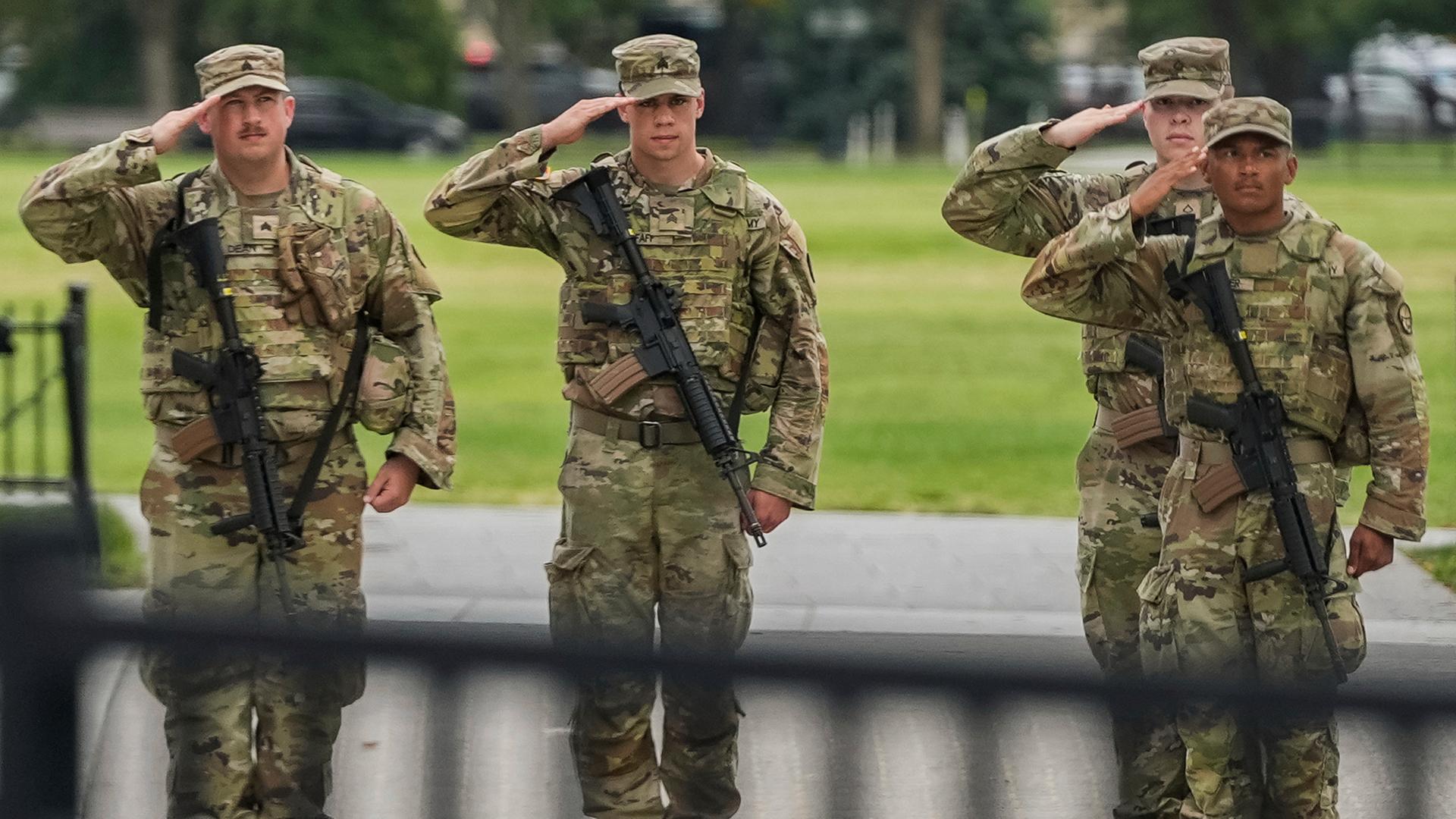 Soldaten der Nationalgarde salutieren, als die Wagenkolonne von Präsident Donald Trump , in Washington vorbeifährt. 