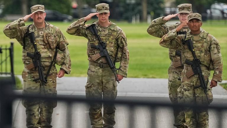  Soldaten der Nationalgarde salutieren, als die Wagenkolonne von Präsident Donald Trump , in Washington vorbeifährt. 