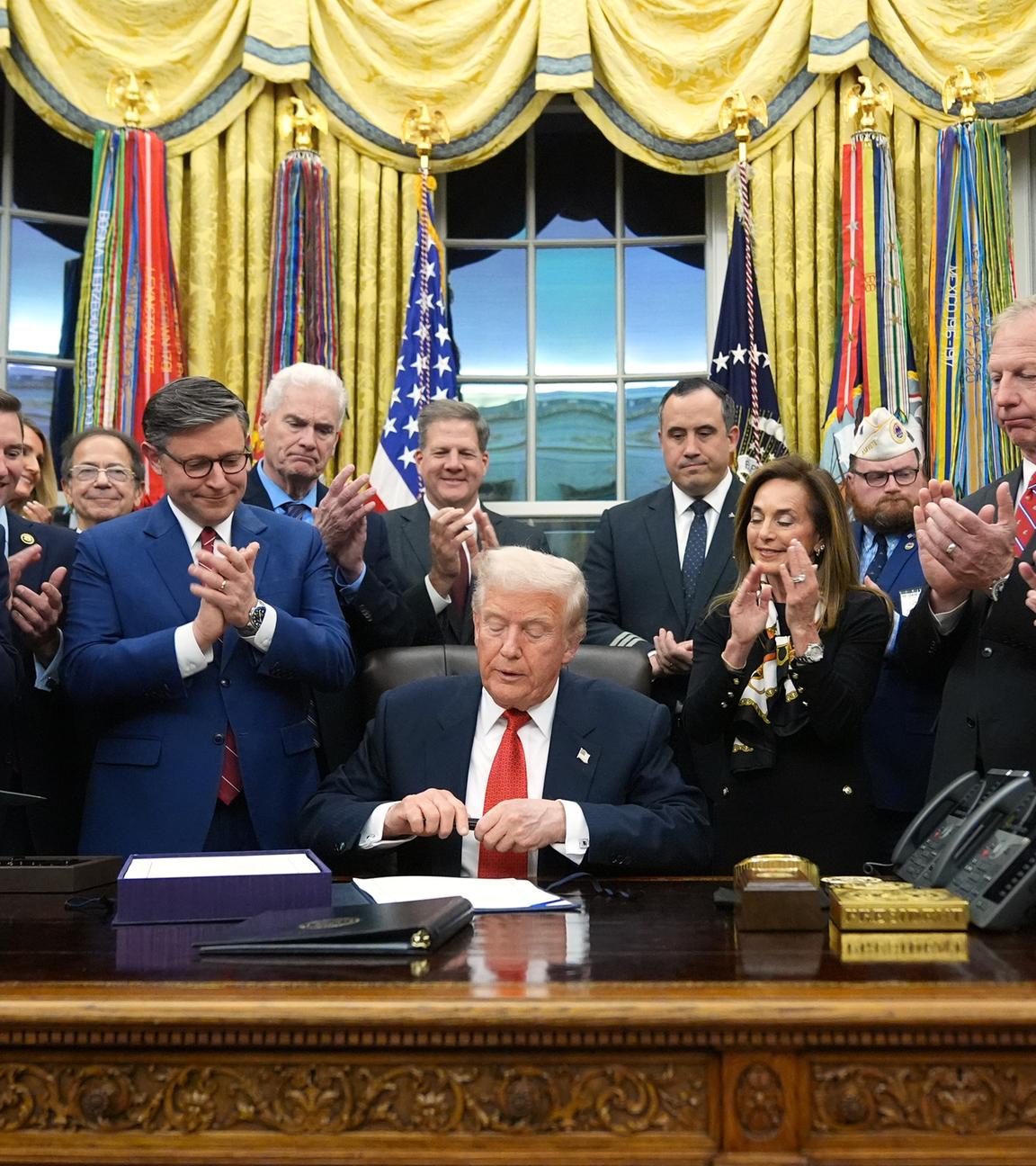 Man erkennt Donald Trump wie er im weißen Haus unterzeichnet