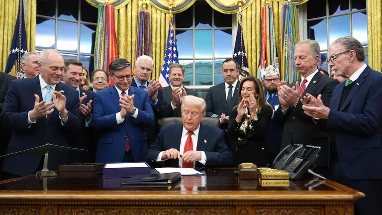 Man erkennt Donald Trump wie er im weißen Haus unterzeichnet