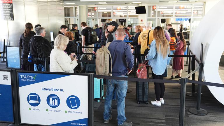 Reisende stehen in einem TSA-Kontrollbereich Schlange.