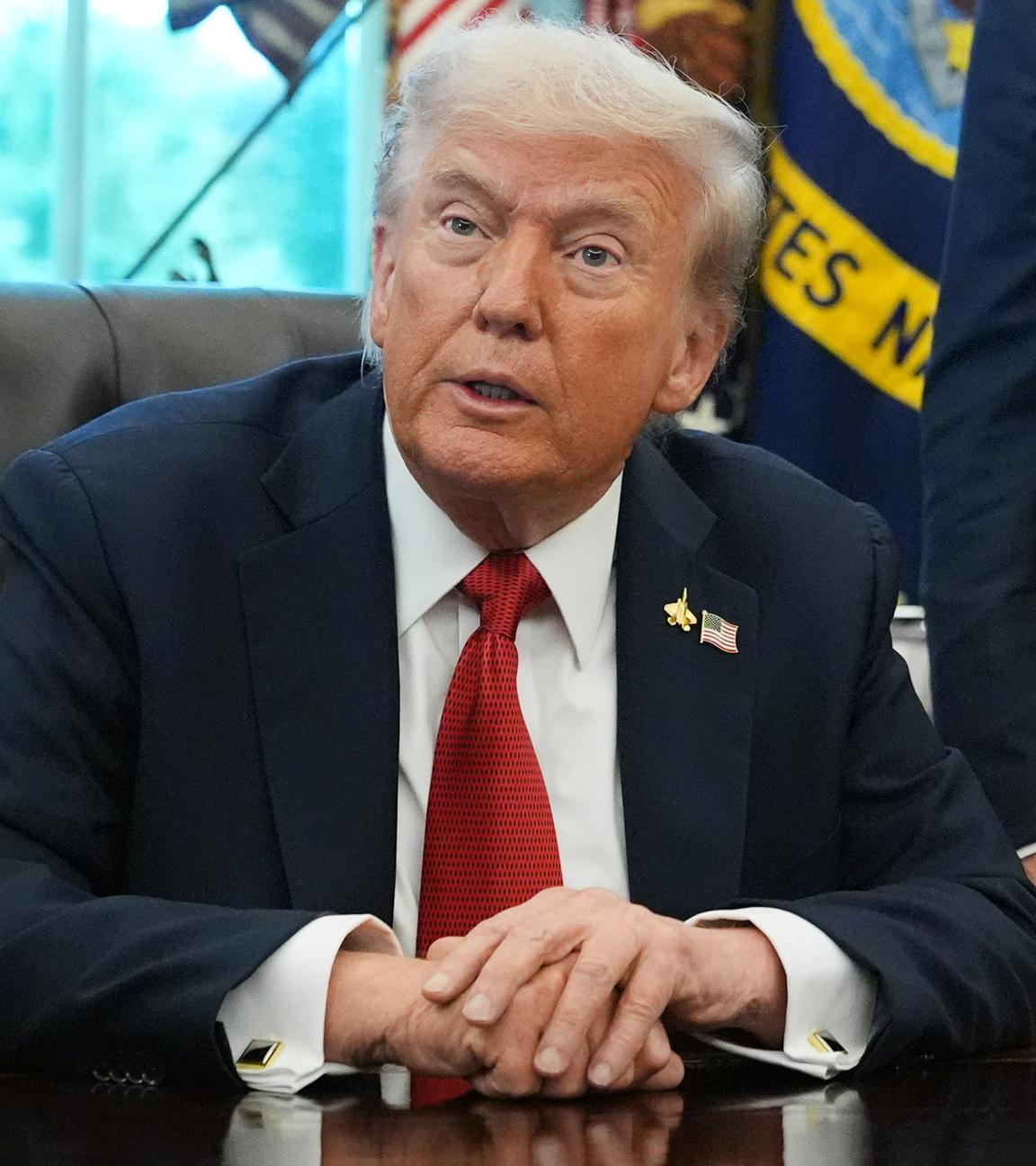 Donald Trump sitzt an einem Tisch im Oval Office