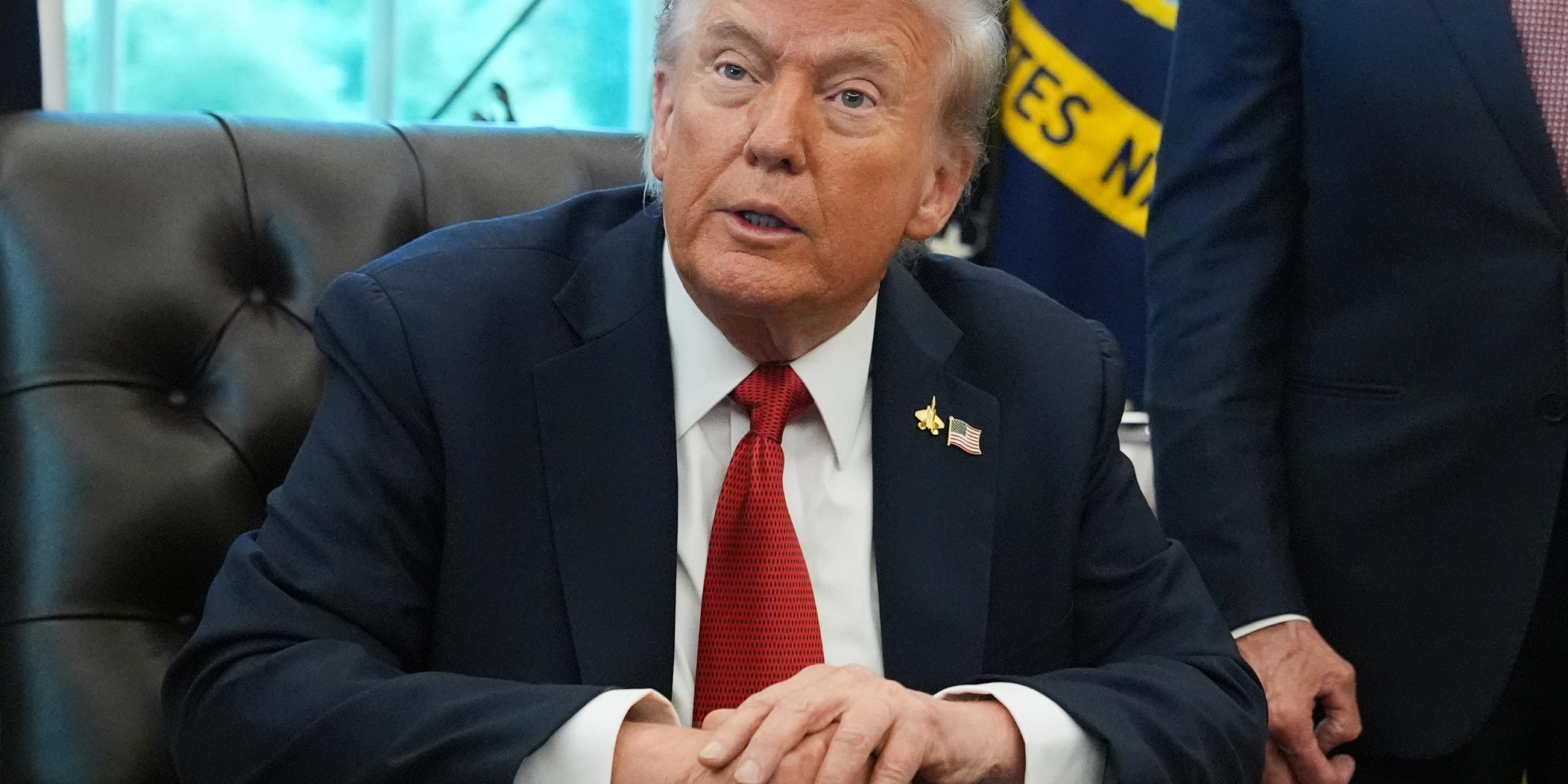Donald Trump sitzt an einem Tisch im Oval Office