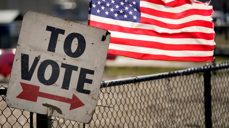 Ein Wahlschild und eine amerikanische Flagge sind vor einem Vorwahlbüro in Dearborn, Michigan zu sehen