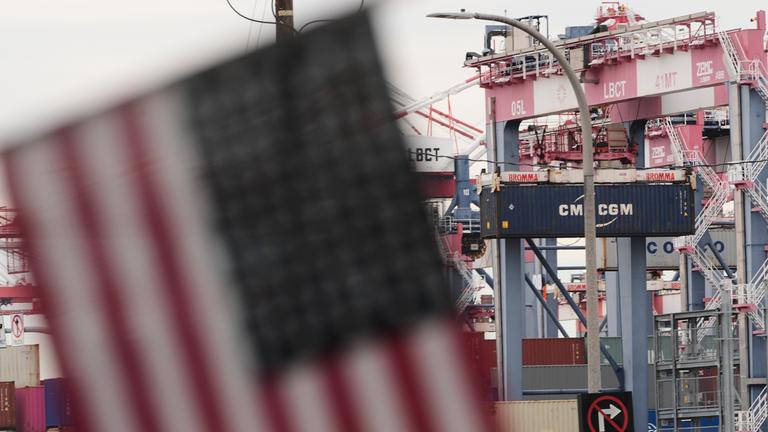 Eine US-Flagge hängt im Hafen vor Containern