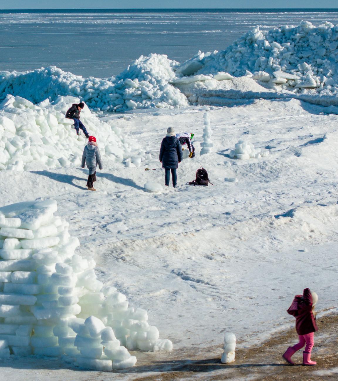 Mecklenburg-Vorpommern, Zempin: Urlauber klettern auf den meterhohen Eisbergen am Ostseestrand auf der Insel Usedom.