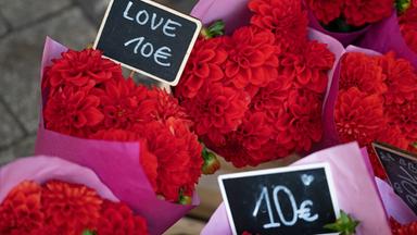 Symbolbild: Gebundene Blumensträuße mit Schildern "Love 10 Euro" werden vor einem Blumengeschäft zum Kauf angeboten.
