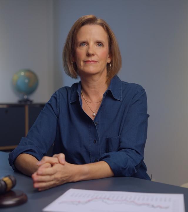 Valerie Haller sitzt an einem Tisch und lächelt in die Kamera.