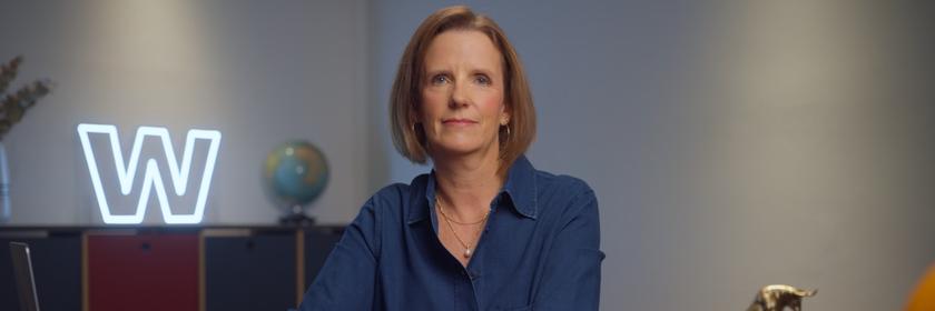 Valerie Haller sitzt an einem Tisch und lächelt in die Kamera.