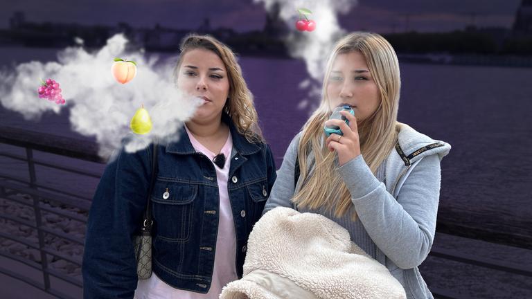 Bearbeitetes Bild: Michelle und Kimberley stehen mit Vapes vor einem dunklen Hintergrund. Aus ihrem Mund dringt Dampf, in dem bunte Fruchtsymbole tanzen.