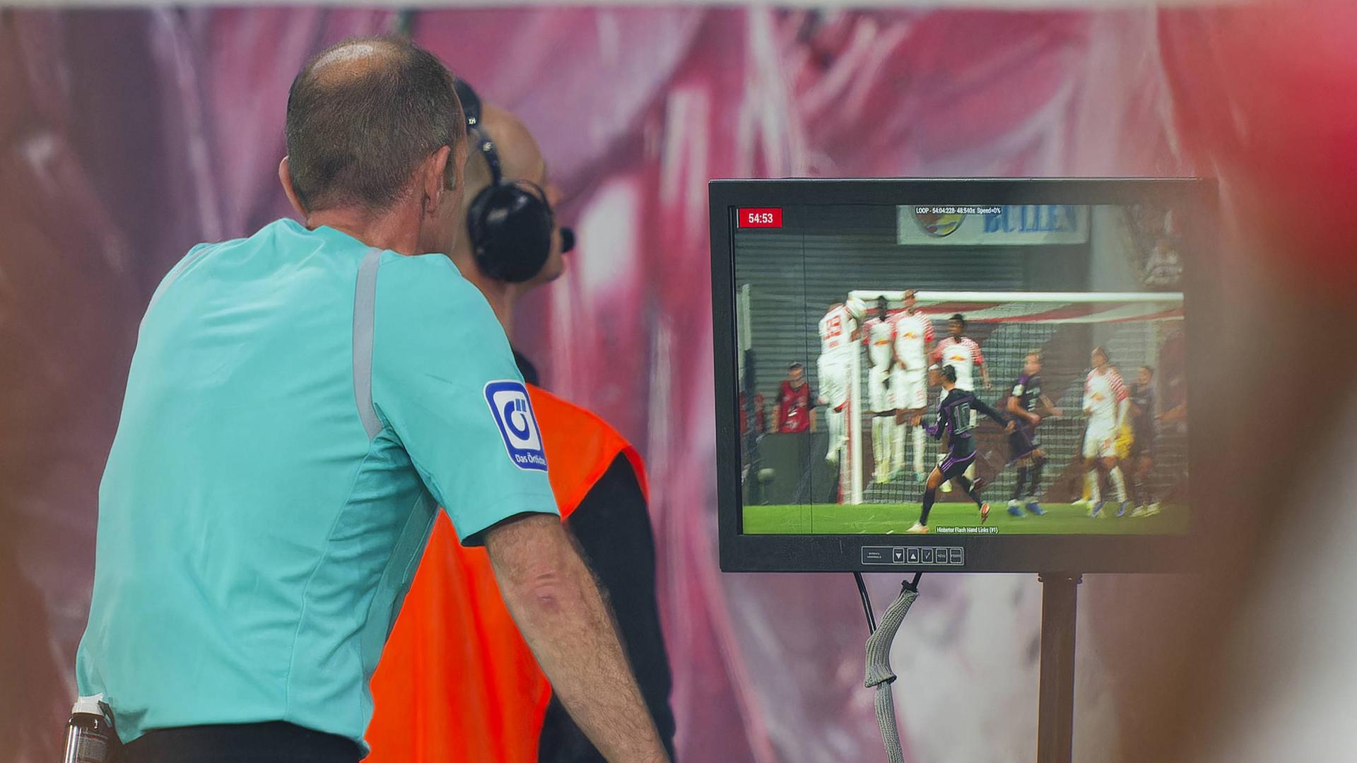 Schiedsriuchter schaut sich eine Szene auf dem Monitor ab