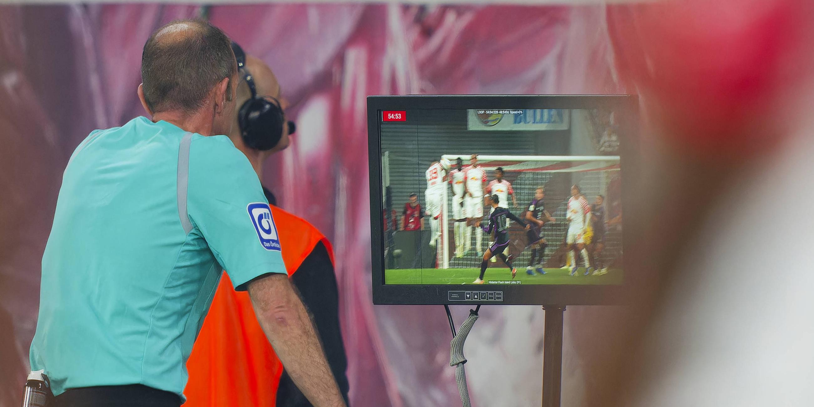 Schiedsriuchter schaut sich eine Szene auf dem Monitor ab
