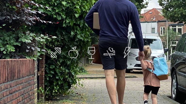 Ein Vater läuft mit seinem Kind an der Hand aus einer Ausfahrt.