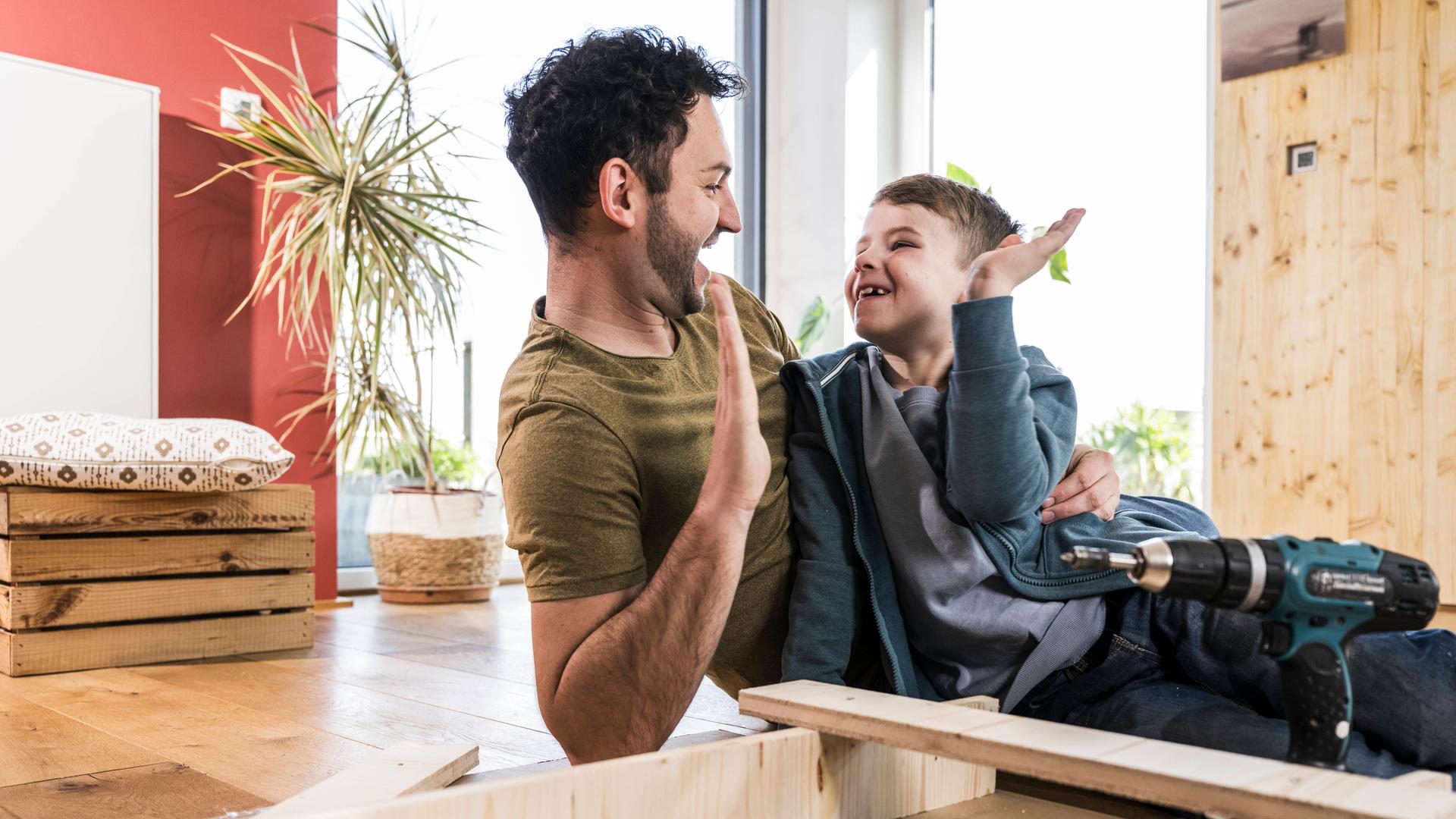 Vater und Sohn klatschen sich beim gemeinsamen Heimwerken in die Hände.