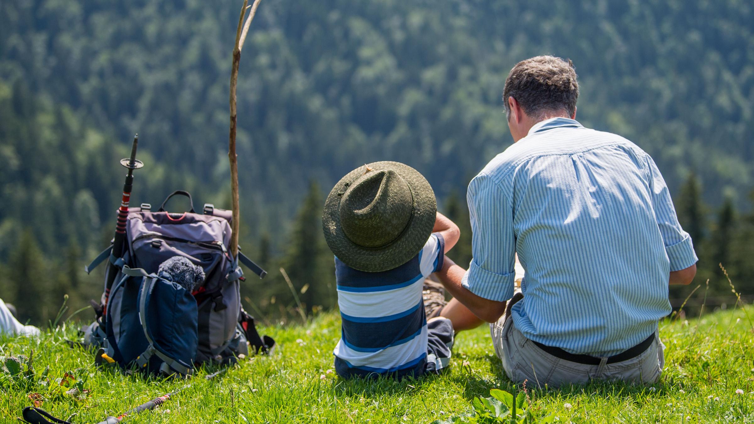 Ein Mann sitzt mit einem Kind auf einer Wiese.