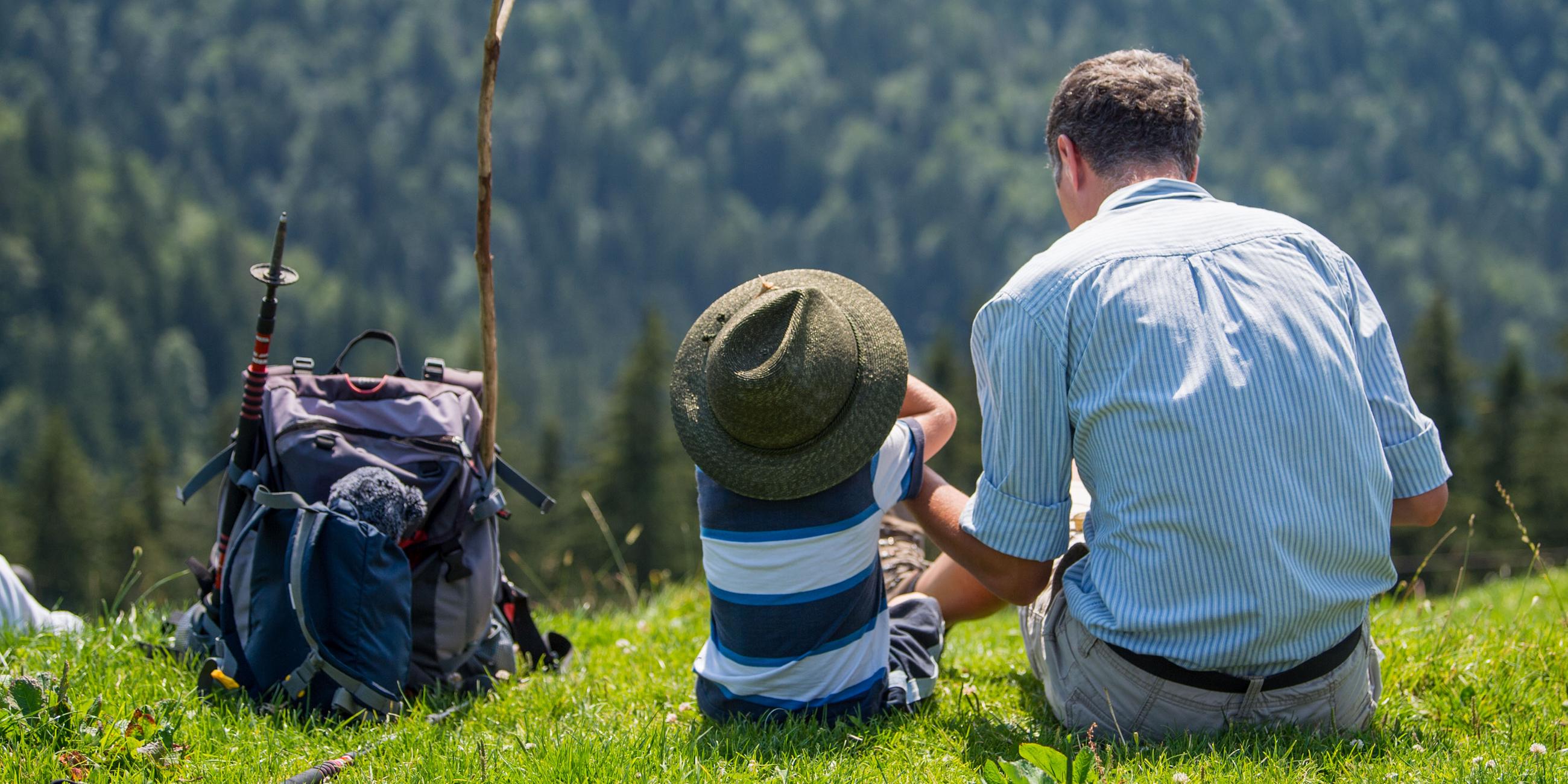 Ein Mann sitzt mit einem Kind auf einer Wiese.