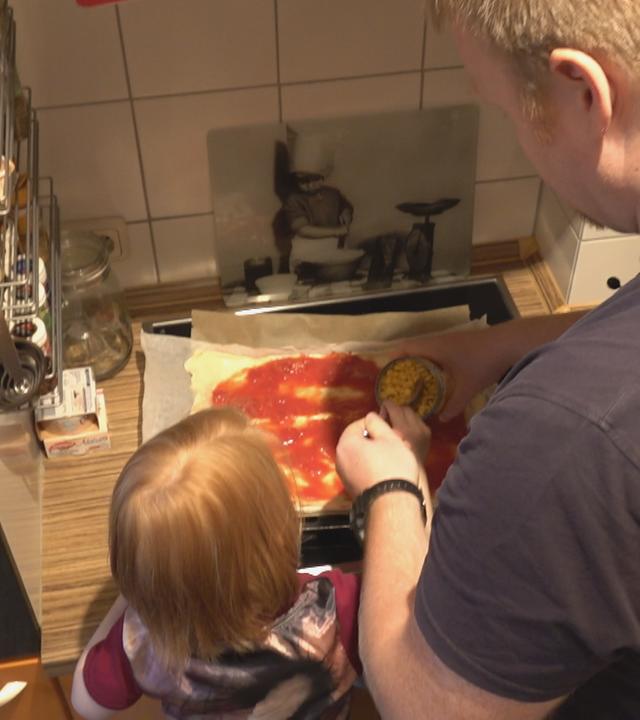 Vater un Tochter beim Pizzazubereiten