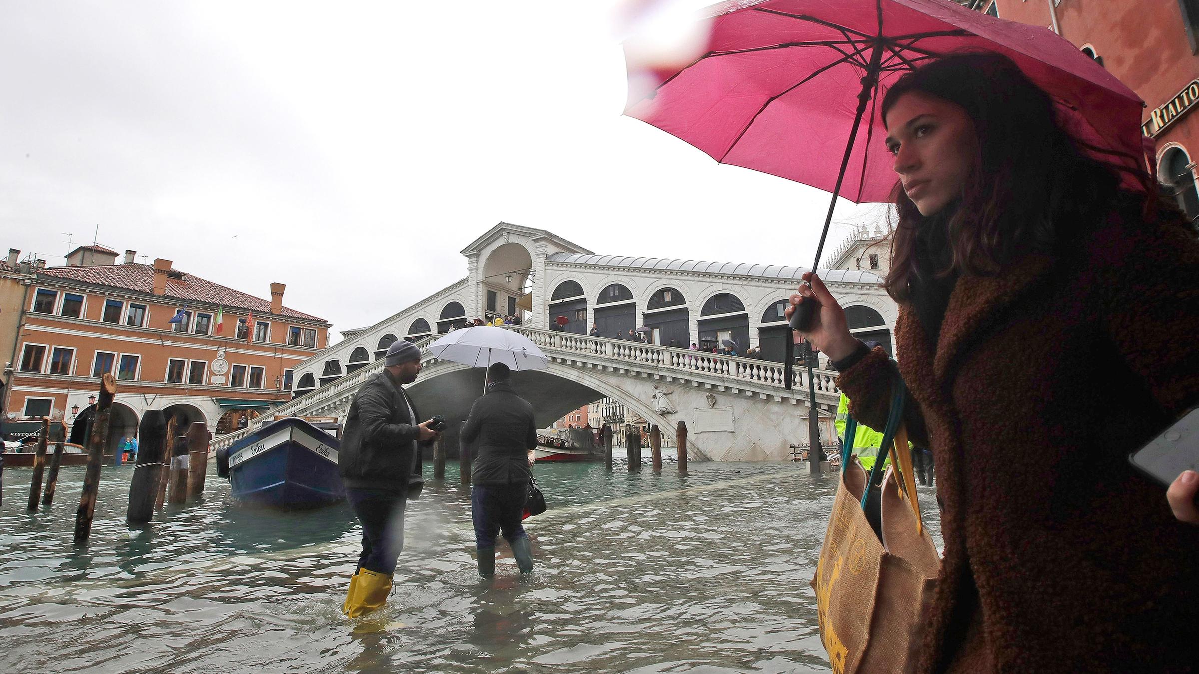 Passanten an der Rialto-Brücke waten durch das Hochwasser.