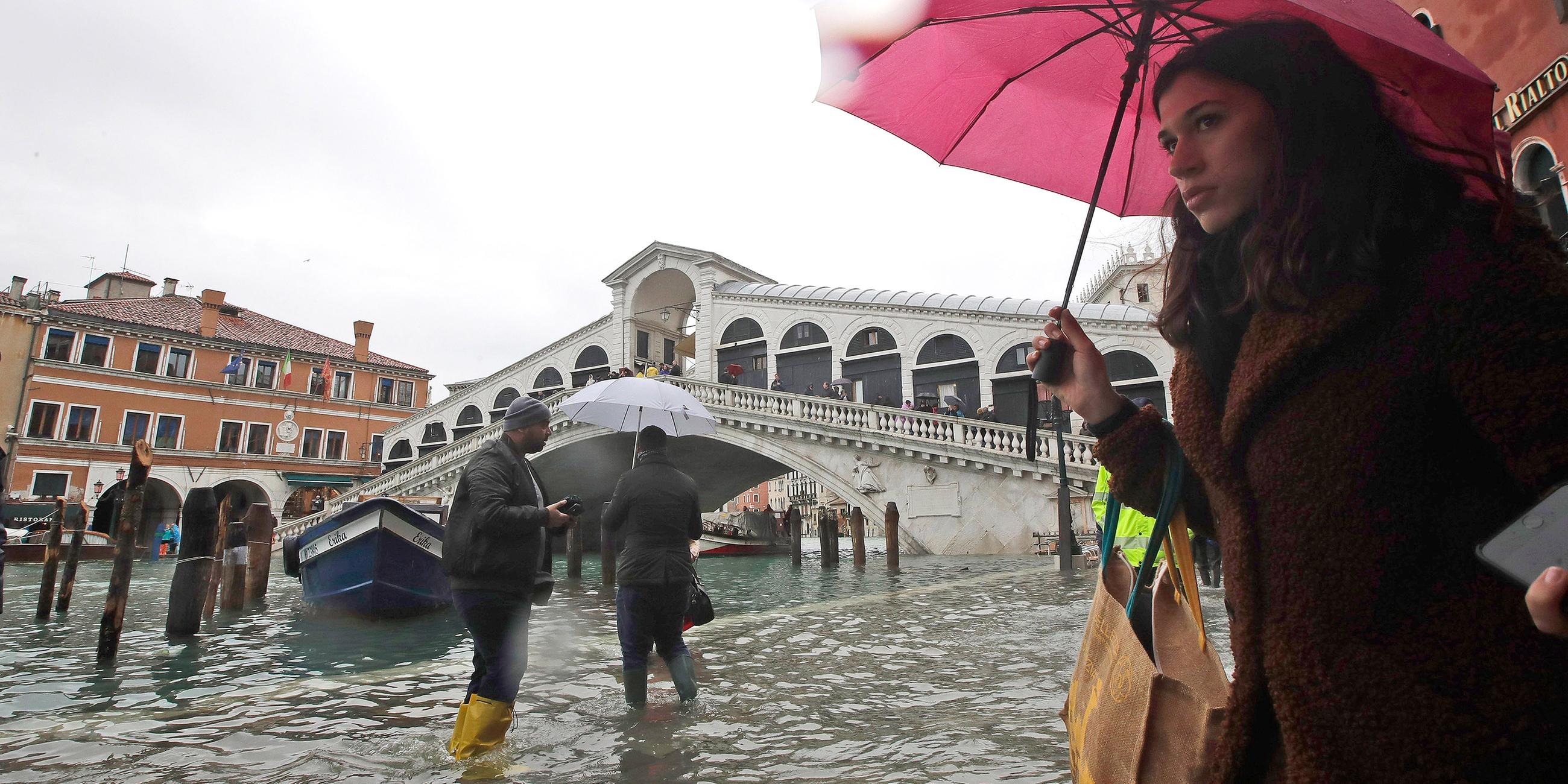 Passanten an der Rialto-Brücke waten durch das Hochwasser.