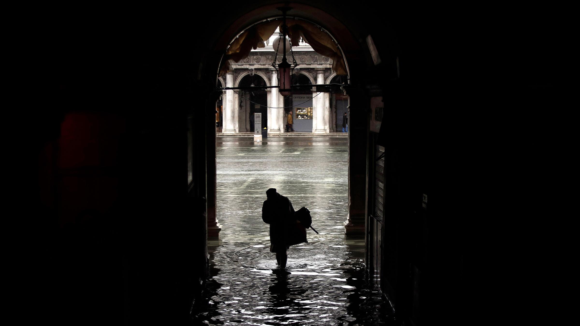 Eine Frau watet durch die Fluten am Markusplatz.