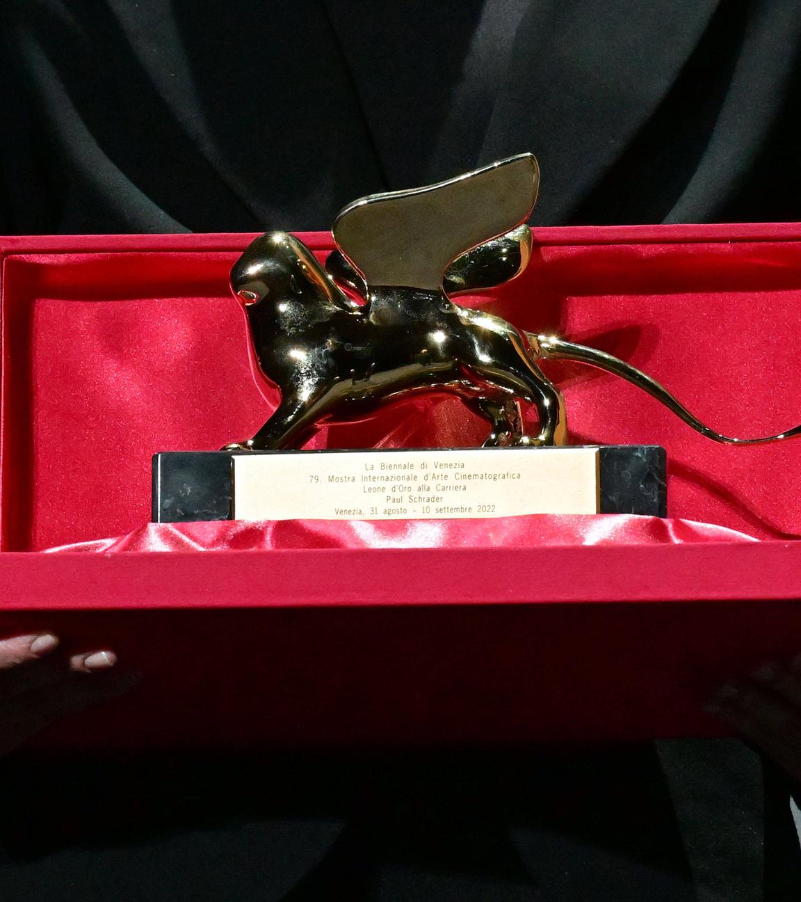 Eine Person hält die Auszeichnung des Goldenen Löwen vom Filmfest Venedig in den Händen.