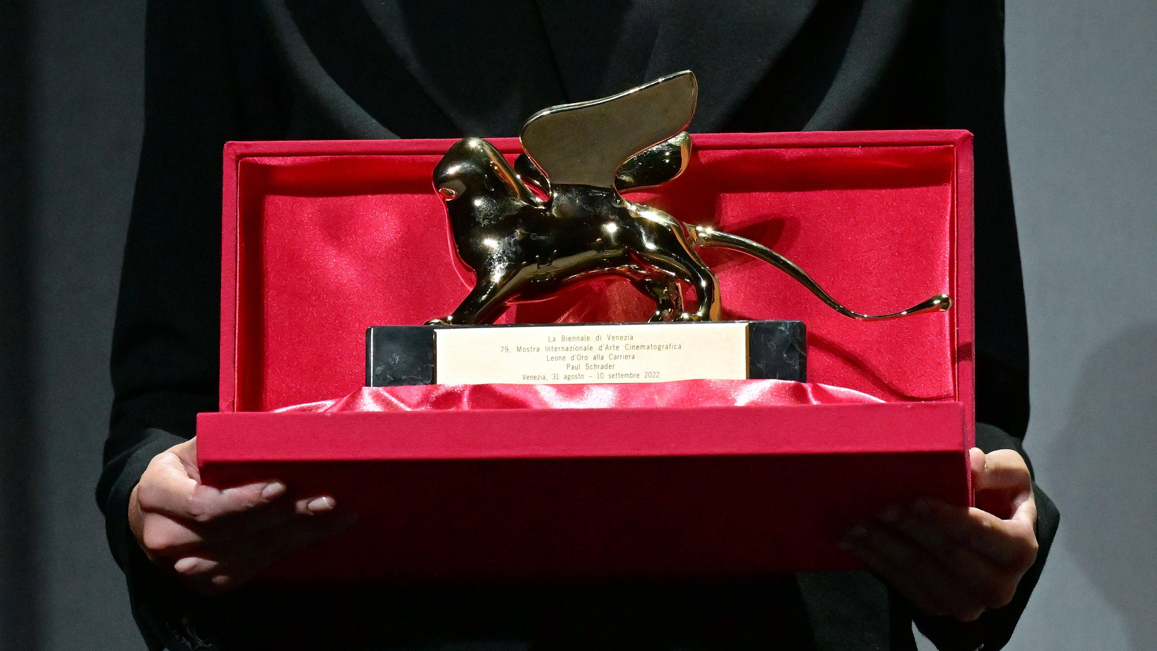 Eine Person hält die Auszeichnung des Goldenen Löwen vom Filmfest Venedig in den Händen.