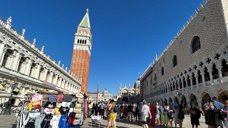 Venedig: Touristen stehen auf dem Markusplatz mit Campanile (M.) und Dogenpalast (r.)