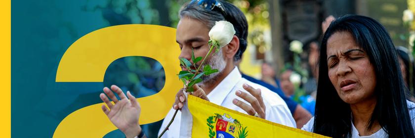 Demonstrierende in Venezuela halten Flagge und weiße Rosen