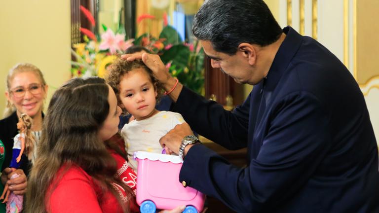 Yorely Bernal (l) trägt ihre Tochter Maikelys Espinoza (M) nach ihrer Ankunft in Venezuela auf dem Arm, während der venezolanische Präsident Nicolas Maduro das Kind streichelt.