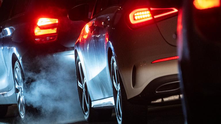 Autoabgase sind hinter einem Kraftfahrzeug im Straßenverkehr zu sehen. 