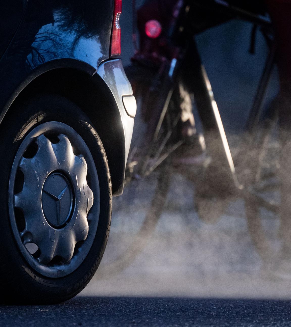 23.11.2021, Baden-Württemberg, Stuttgart: Ein Radfahrer steht neben einem Auto von Mercedes mit Dieselantrieb, dessen Abgase in der kalten Morgenluft sichtbar werden. 