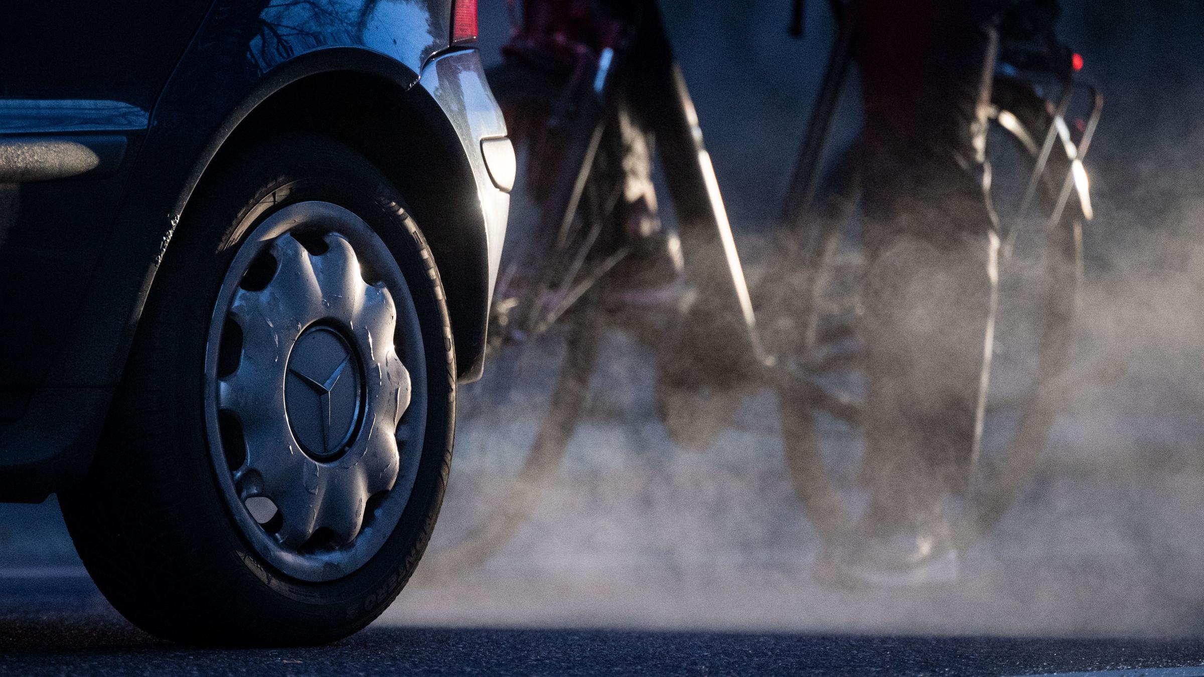23.11.2021, Baden-Württemberg, Stuttgart: Ein Radfahrer steht neben einem Auto von Mercedes mit Dieselantrieb, dessen Abgase in der kalten Morgenluft sichtbar werden. 