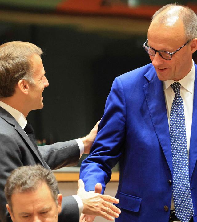 Frankreichs Präsident Emmanuel Macron (links) begrüßt Deutschlands Bundeskanzler Friedrich Merz vor einem Gespräch am runden Tisch im Rahmen eines Gipfeltreffens der Europäischen Union am EU-Hauptsitz in Brüssel am 15.10.2026.