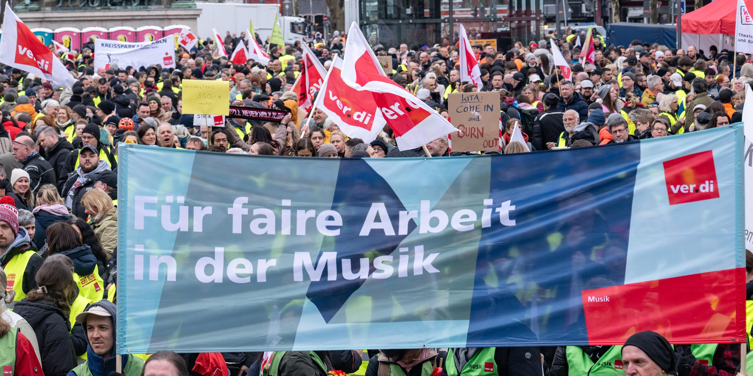 Ein Banner mit der Aufschrift "Für faire Arbeit in der Musik" ist bei einer Kundgebung von Verdi und der GEW auf dem Heumarkt zu sehen.