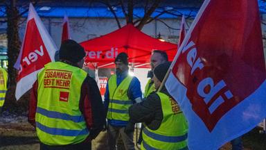Streikende halten Fahnen der Gewerkschaft Verdi und sind mit Warnwesten gekleidet.
