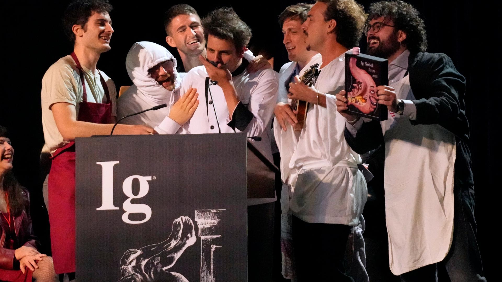 Der Ig-Nobelpreis für Ernährung wird von Daniele Dendi, Gabriel H. Segniagbeto, Roger Meek und Luca Luiselli entgegengenommen, die untersucht haben, inwieweit eine bestimmte Eidechsenart bestimmte Sorten von Pizza isst.