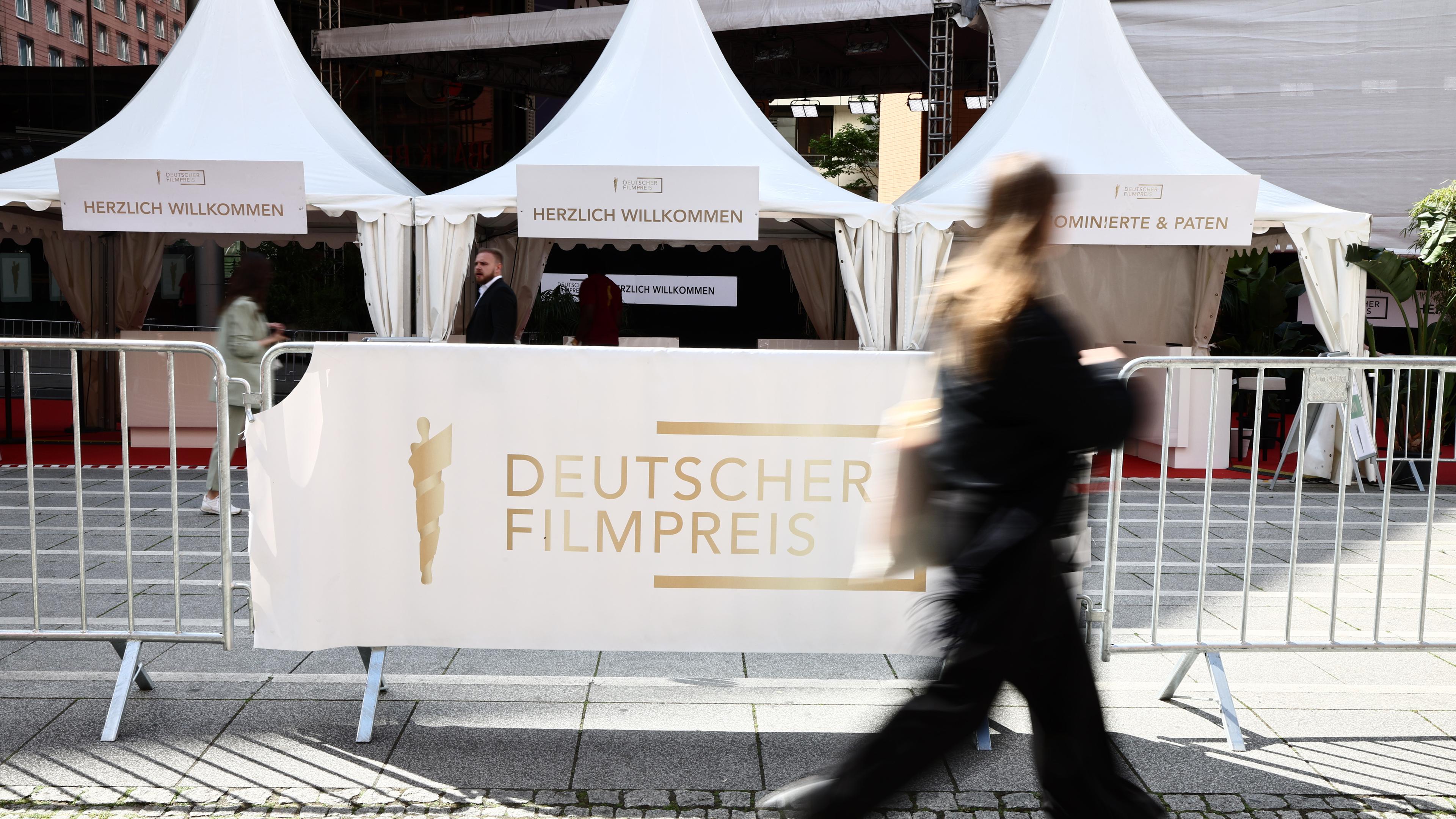 Eine Frau geht am Schriftzug "Deutscher Filmpreis" centlang vor der 75. Verleihung des Deutschen Filmpreises in Berlin vorbei.