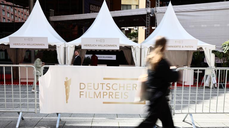 Eine Frau geht am Schriftzug "Deutscher Filmpreis" centlang vor der 75. Verleihung des Deutschen Filmpreises in Berlin vorbei.