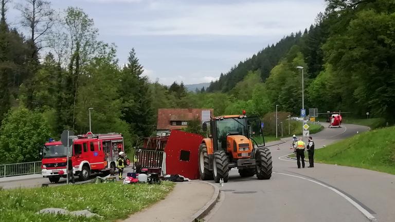 Baden-Württemberg, Kandern: Rettungskräfte stehen nach einem Unfall neben einem einem umgestürzten Maiwagen.