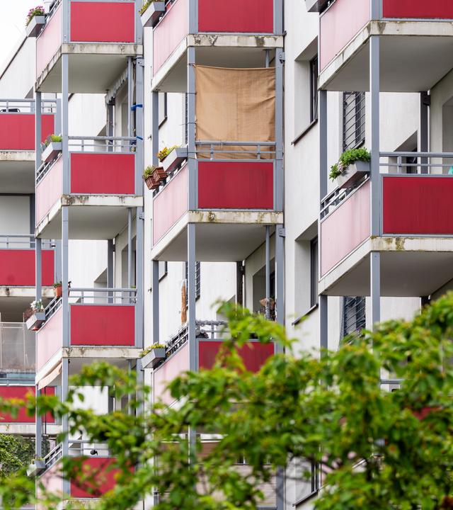 Rote Balkone an einem mehrstöckigen Wohnhaus.