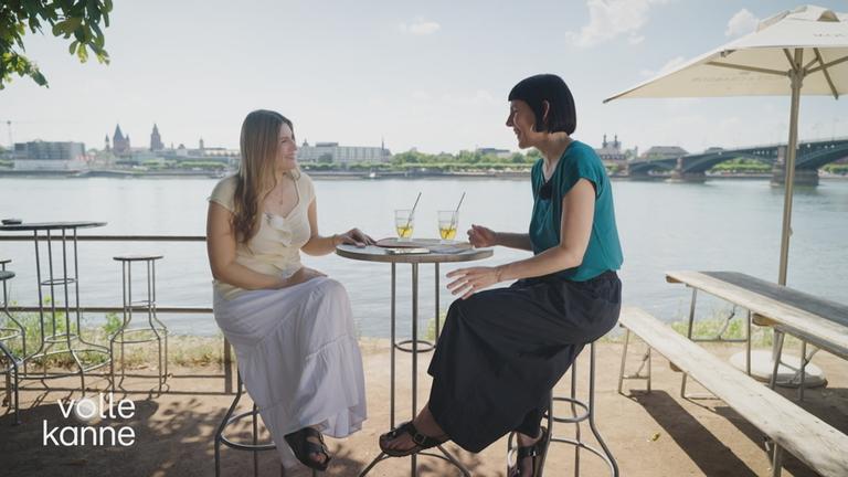 Zwei Frauen sitzen an einem Tisch mit Getränken