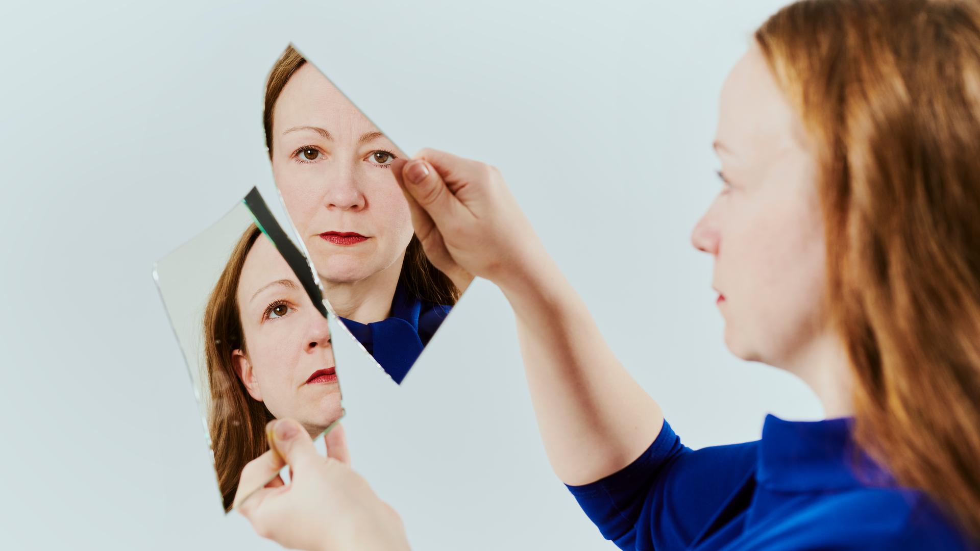 Zwei Spiegelscherben werden von zwei Händen hochgehalten. Im Spiegelbild zusehen ist Alexandra.