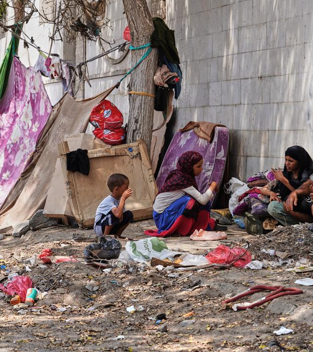 11.10.2026, Jemen, Aden: Eine vertriebene jemenitische Familie sitzt neben einer provisorischen Unterkunft am Straßenrand in Aden.