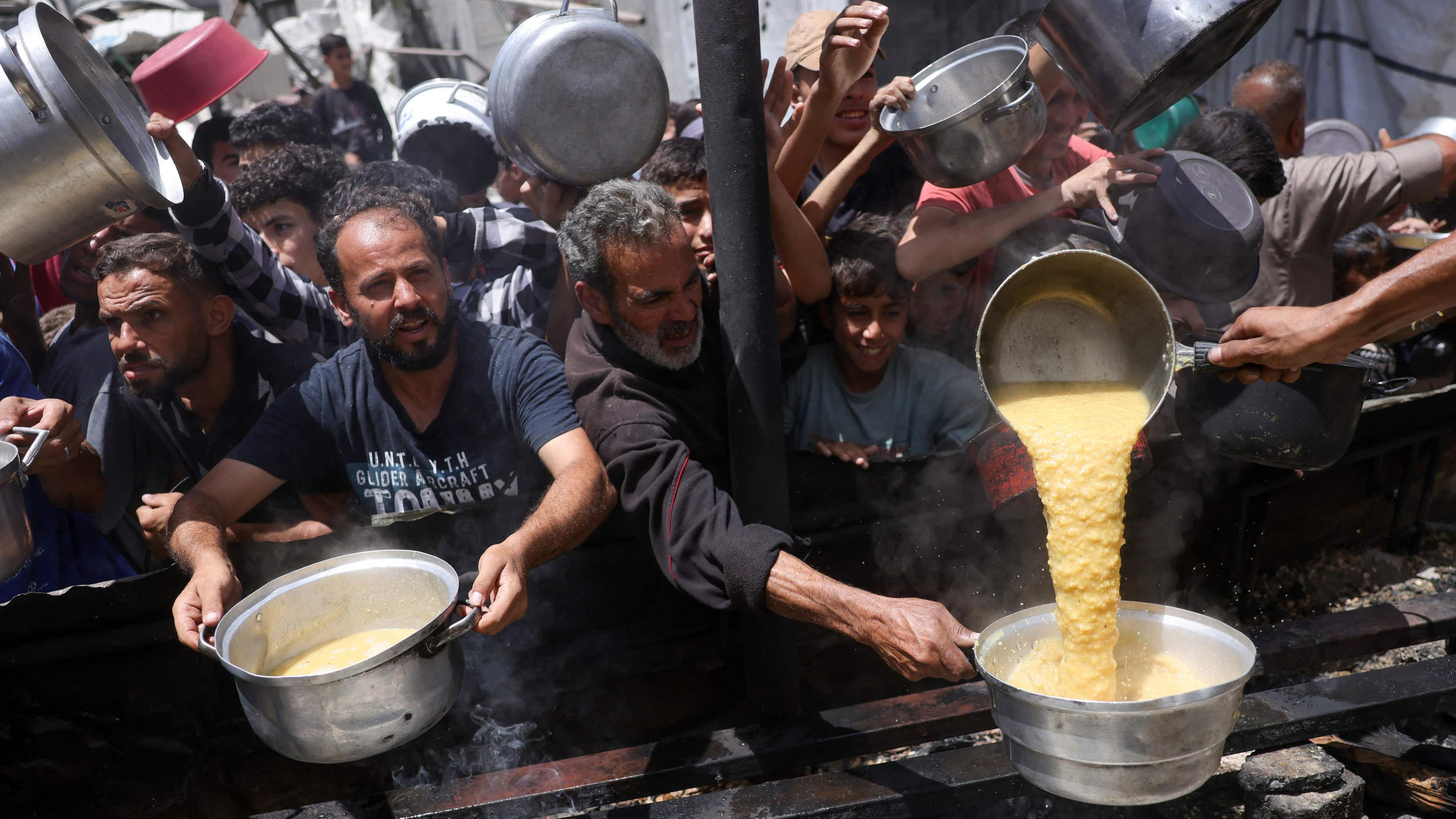 Vertriebene Palästinenser sammeln bei einer Wohltätigkeitsveranstaltung in Dschabalija im nördlichen Gazastreifen gekochte Speisen.