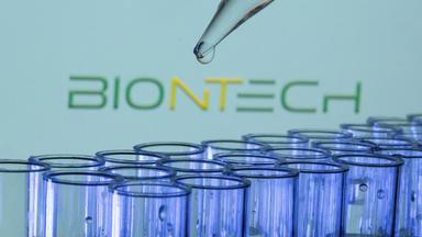 Teströhrchen vor Biontech-Logo