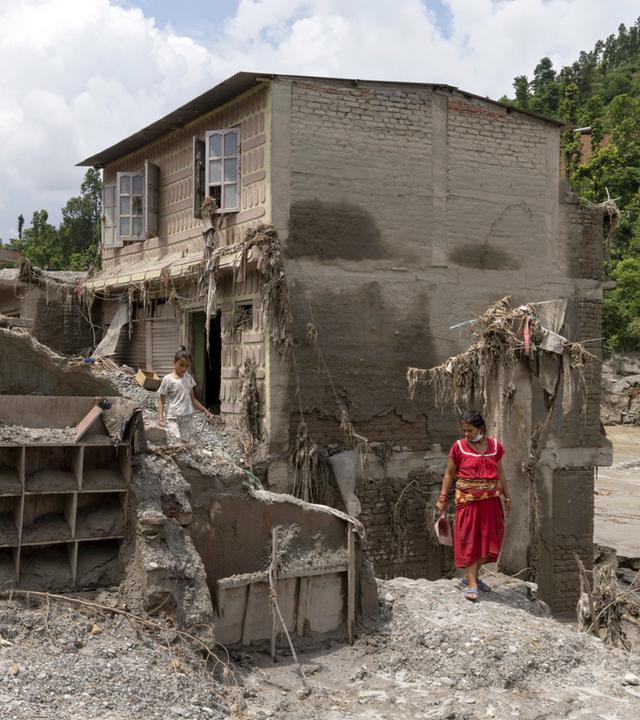 Anwohner versuchen in den beschädigten Häusern nach Sturzfluten, entlang des Ufers des Trishuli-Flusses im Distrikt Dhading, Nepal, am 30.08.2026 persönliche Gegenstände zu retten. 