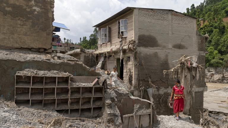 Anwohner versuchen in den beschädigten Häusern nach Sturzfluten, entlang des Ufers des Trishuli-Flusses im Distrikt Dhading, Nepal, am 30.08.2026 persönliche Gegenstände zu retten. 