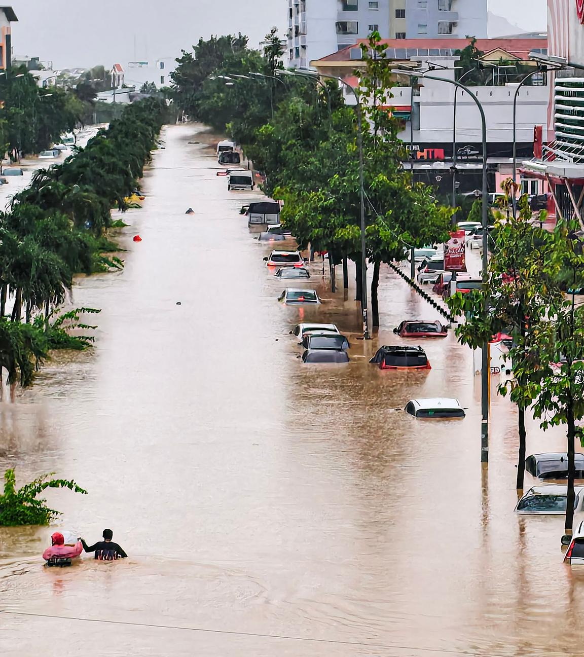 Vietnam, Küstenprovinz Khanh Hoa: Menschen suchen einen Weg durch überflutete Straßen.